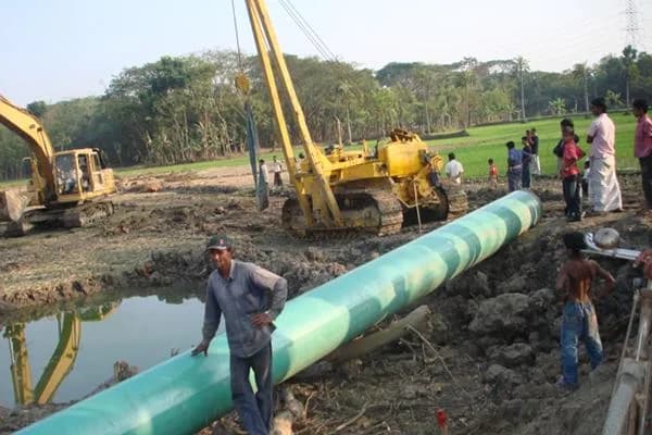 Crew lowering a coated gas pipe into the trench